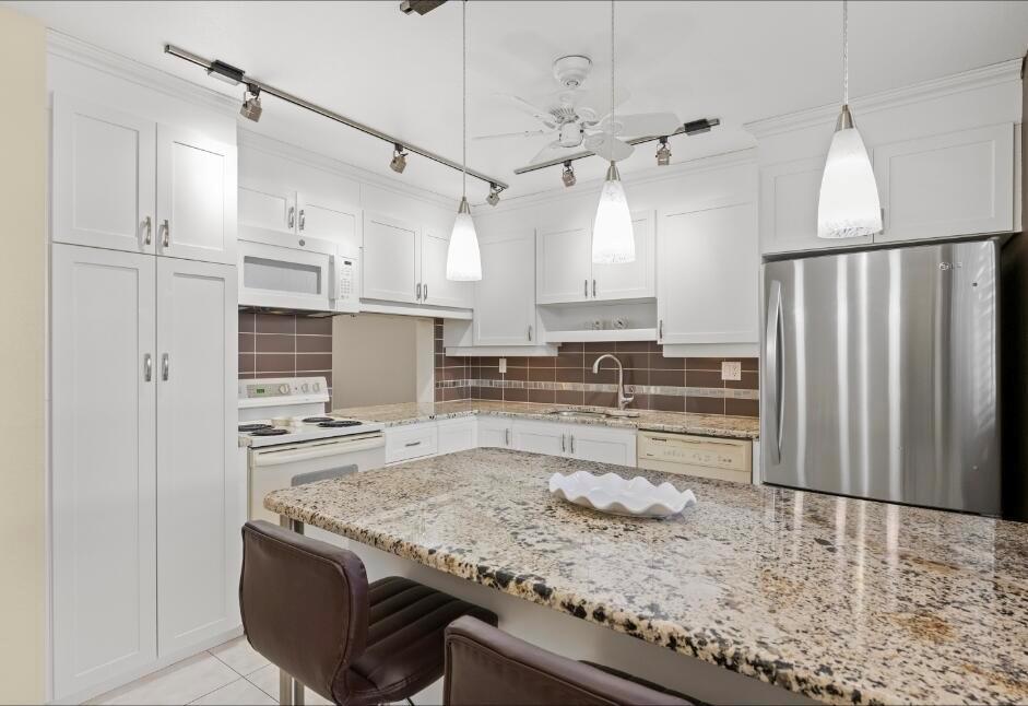 A kitchen with white cabinetry, granite countertops, stainless steel appliances, and a central island — 6095 N Sabal Palm Boulevard # 210, Tamarac FL 33319, TAMARAC, FL