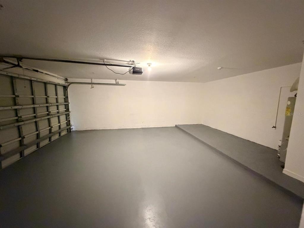 An empty garage with a gray painted floor, white walls, and a metal roll-up door — 1807 SHADOW VIEW CIRCLE UNIT 1807, MAITLAND, FL