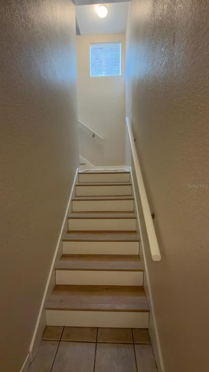 A staircase with light wood treads and white risers leads up to a landing with windows — 1807 SHADOW VIEW CIRCLE UNIT 1807, MAITLAND, FL