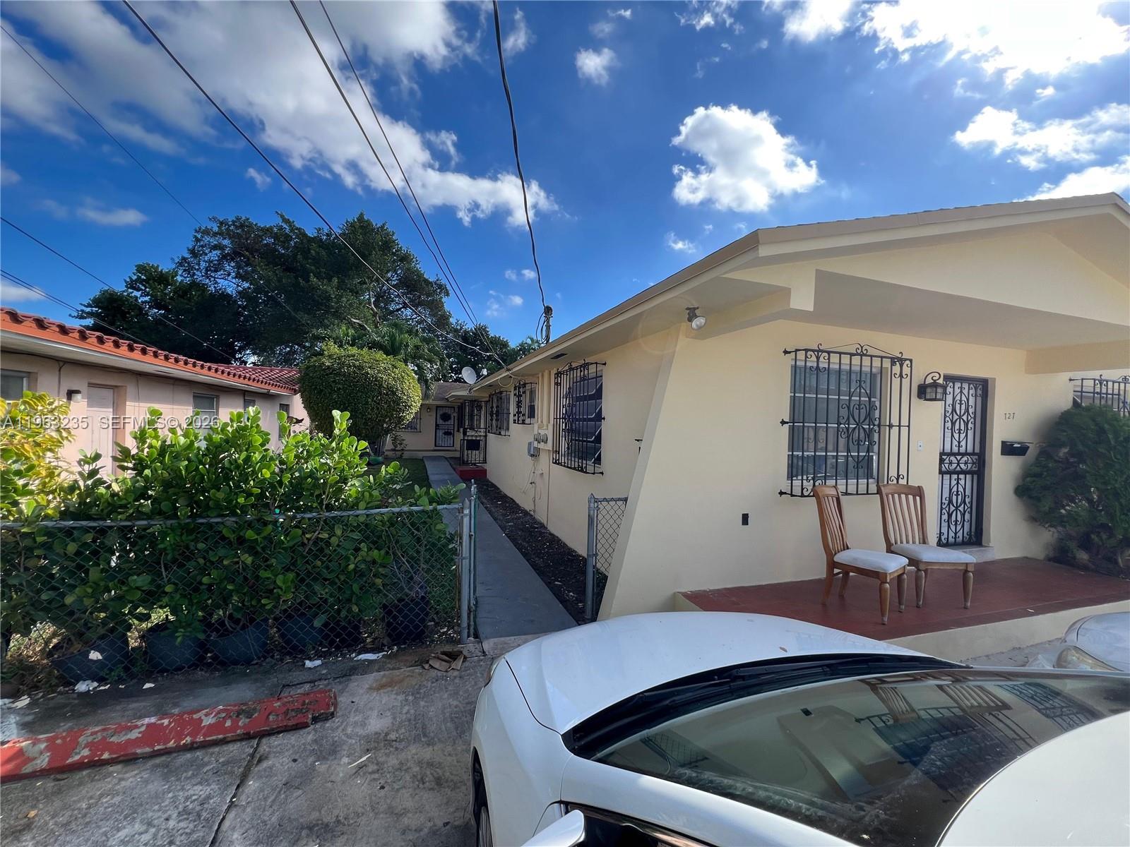 A light yellow house exterior features a front porch with two chairs and security bars — 733 NW 33rd Ave, Miami FL 33125, MIAMI, FL