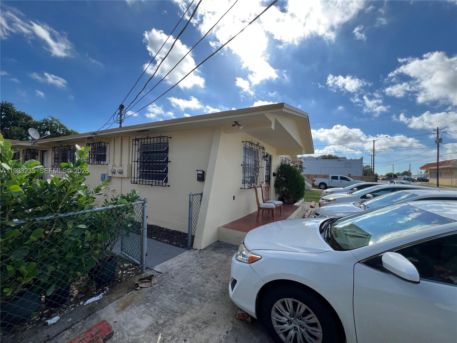 An exterior view of a single-story house with a white car parked in the driveway — 733 NW 33rd Ave, Miami FL 33125, MIAMI, FL