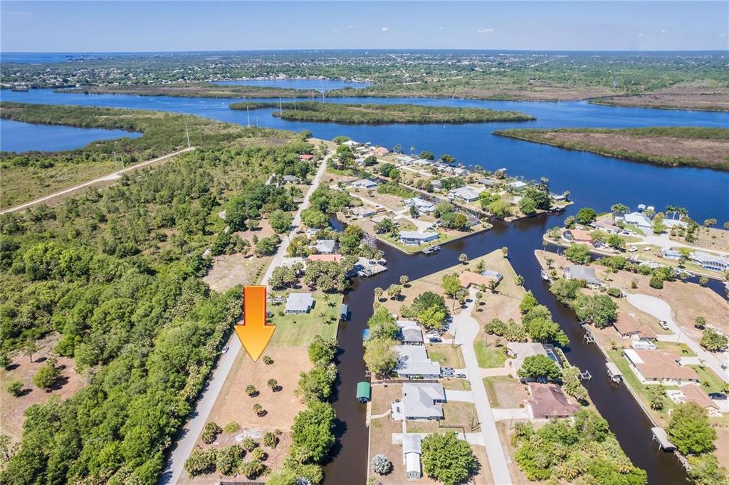 An aerial view shows a vacant, grassy lot situated along a canal in a residential area — 28426 & 28434 ROYAL PALM DRIVE, PUNTA GORDA, FL