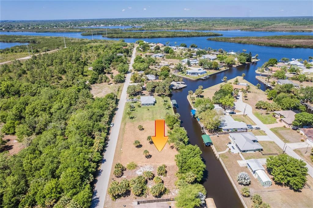 An aerial view shows a vacant waterfront lot with an orange arrow pointing downward — 28426 & 28434 ROYAL PALM DRIVE, PUNTA GORDA, FL