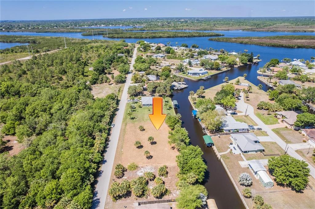 An aerial view shows a vacant waterfront lot situated between a road and a canal — 28426 & 28434 ROYAL PALM DRIVE, PUNTA GORDA, FL