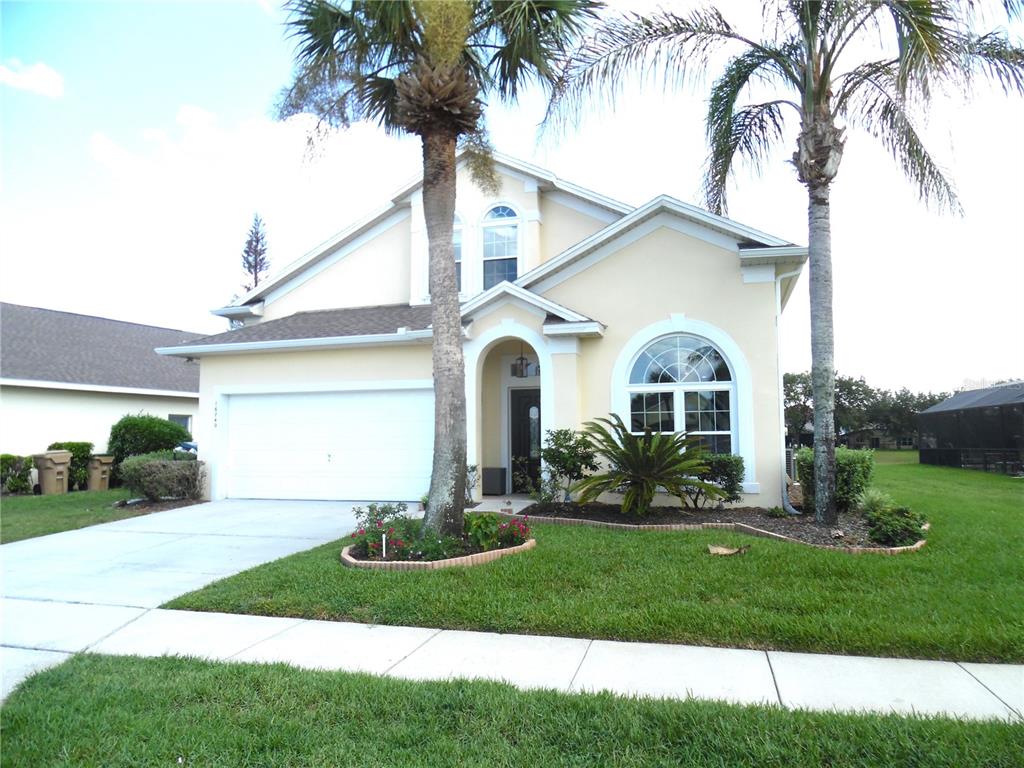 A two-story suburban house with a white garage, arched entryway, and two palm trees — 16740 GLENBROOK BOULEVARD, CLERMONT, FL