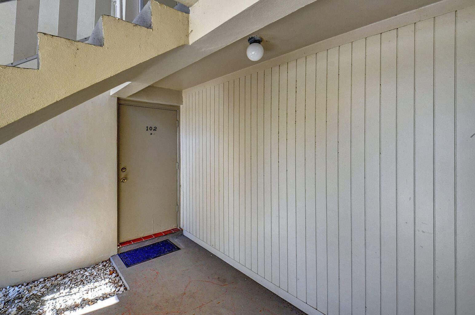 An exterior view of a building entrance featuring a door labeled 102 and stairs — 315 Circle Drive S # 102, Boynton Beach FL 33435, BOYNTON BEACH, FL