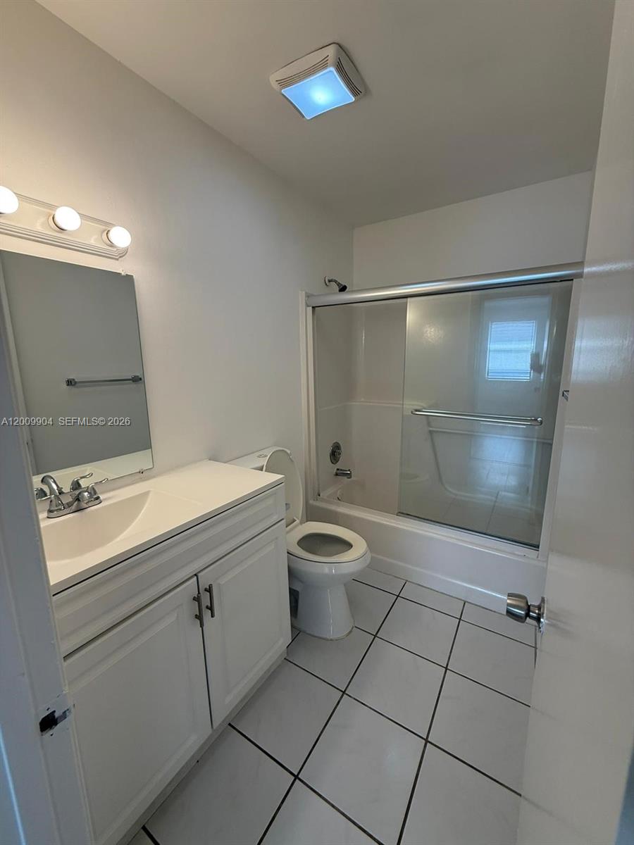 A bathroom features a white vanity, a toilet, and a shower-tub combination with glass doors — 16413 Grape Way, Delray Beach FL 33484, DELRAY BEACH, FL