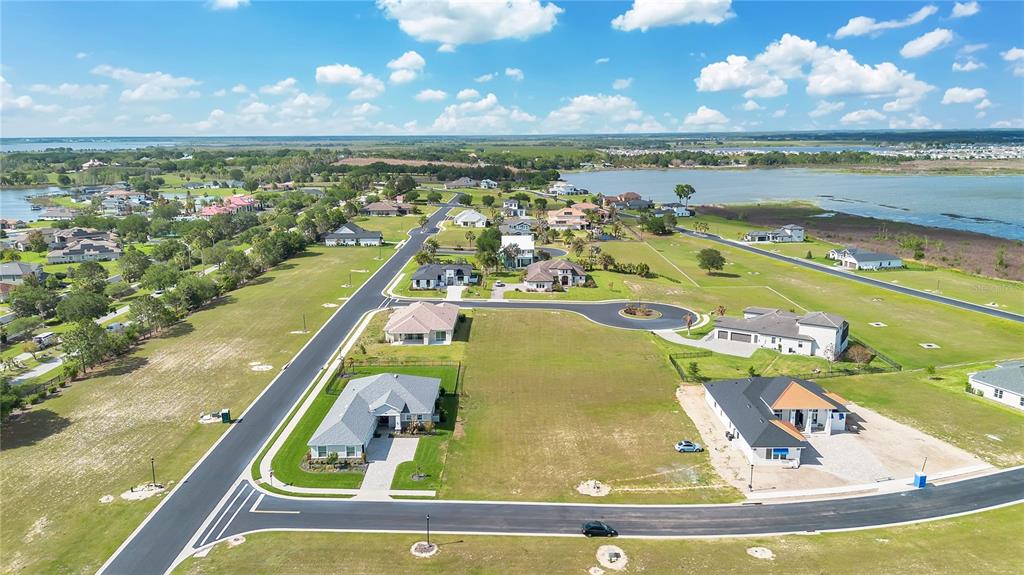 An aerial view shows several suburban houses situated on large lots near a lake — 228 SNOWY ORCHID WAY, LAKE ALFRED, FL