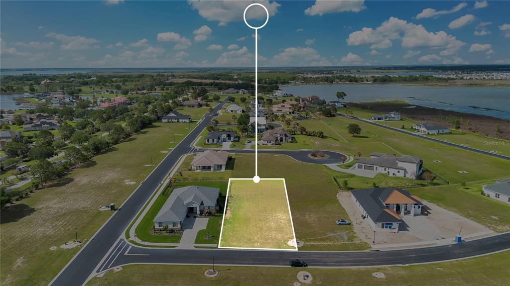 An aerial view shows a vacant residential lot outlined in white within a suburban neighborhood — 228 SNOWY ORCHID WAY, LAKE ALFRED, FL