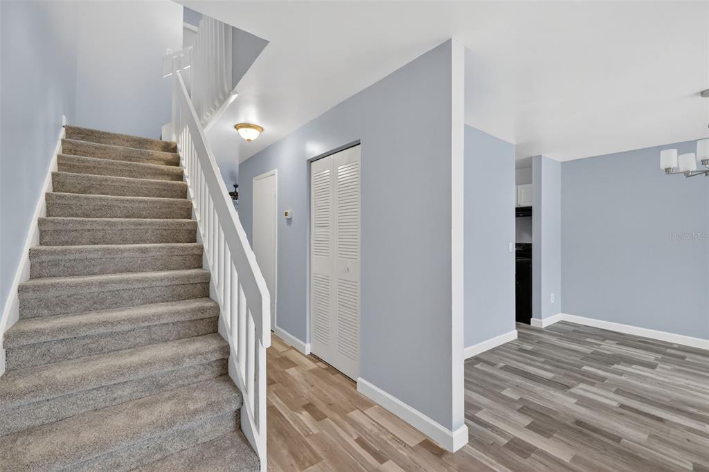 A carpeted staircase leads to an upper level next to a hallway with wood-look flooring — 5121 PICADILLY CIRCUS COURT, ORLANDO, FL