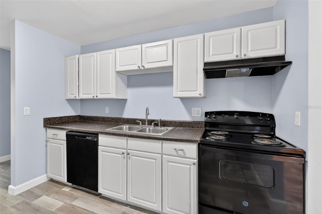 A kitchen features white cabinets, dark countertops, a black dishwasher, and a black electric stove — 5121 PICADILLY CIRCUS COURT, ORLANDO, FL