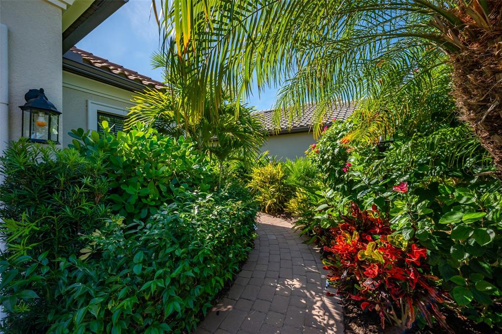 A screened-in patio features a brick floor, outdoor furniture, a fountain, and a lake view — 5451 LAGO MAGGIO STREET, SARASOTA, FL