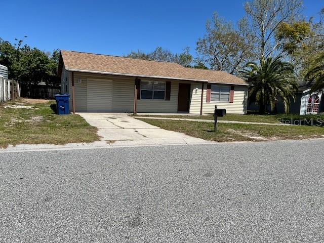 A single-story house with tan siding, a shingled roof, and a concrete driveway — 6413 SUTTERS MILL ROAD, NEW PORT RICHEY, FL