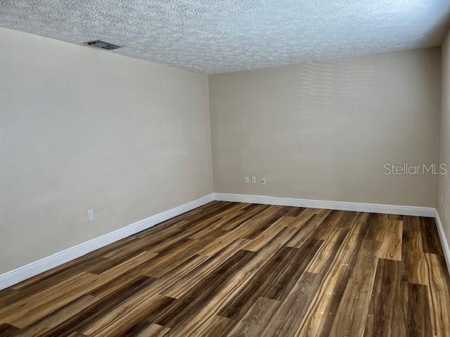 An empty room features light-colored walls, white trim, and wood-look plank flooring — 6413 SUTTERS MILL ROAD, NEW PORT RICHEY, FL