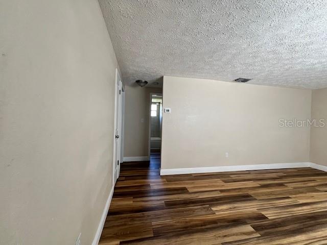 An interior view of a room with light-colored walls and wood-look flooring — 6413 SUTTERS MILL ROAD, NEW PORT RICHEY, FL