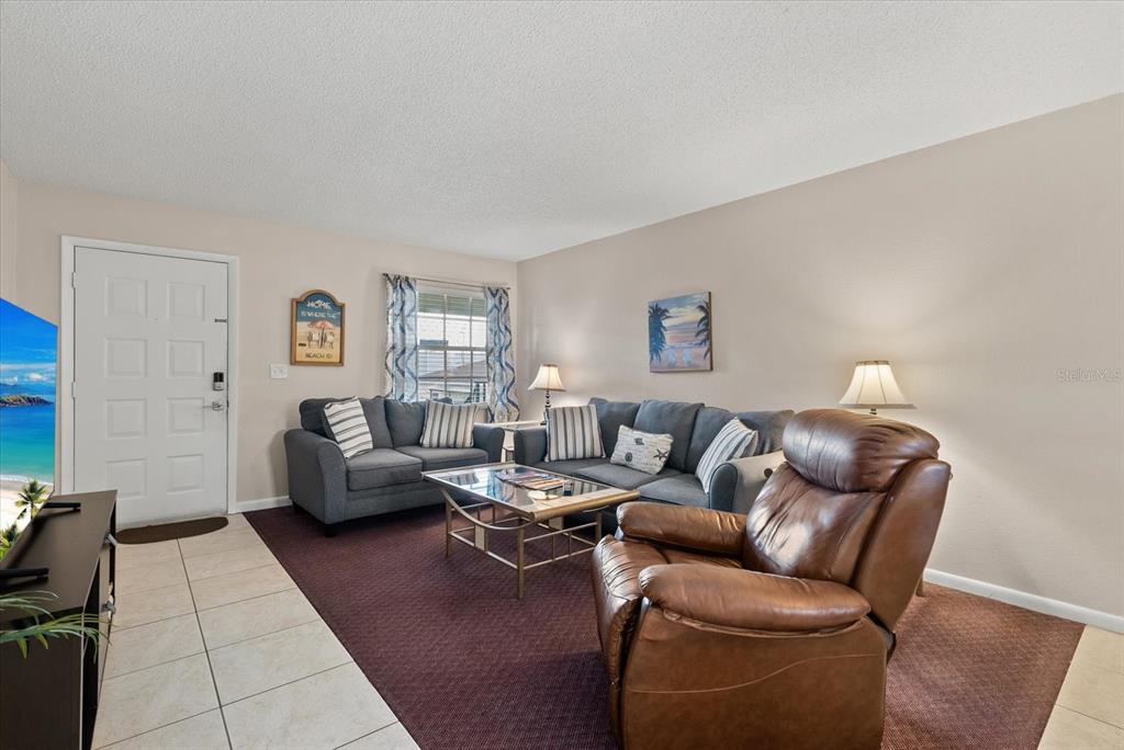 A living room features a grey sectional sofa, a brown leather recliner, and a coffee table — 1531 PLACIDA ROAD UNIT 204, ENGLEWOOD, FL