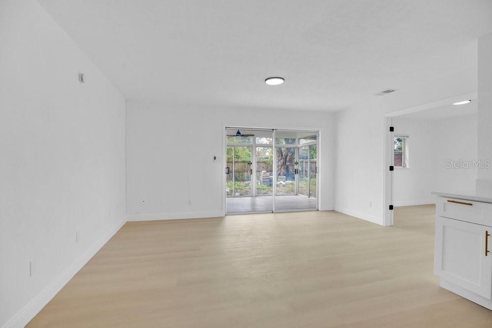 An empty room with light wood floors, white walls, and sliding glass doors to a porch — 1241 MANCHESTER ROAD, MAITLAND, FL