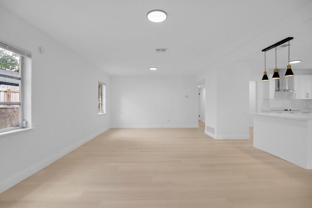 A bright, open-concept living area features white walls, light wood flooring, and a kitchen island — 1241 MANCHESTER ROAD, MAITLAND, FL
