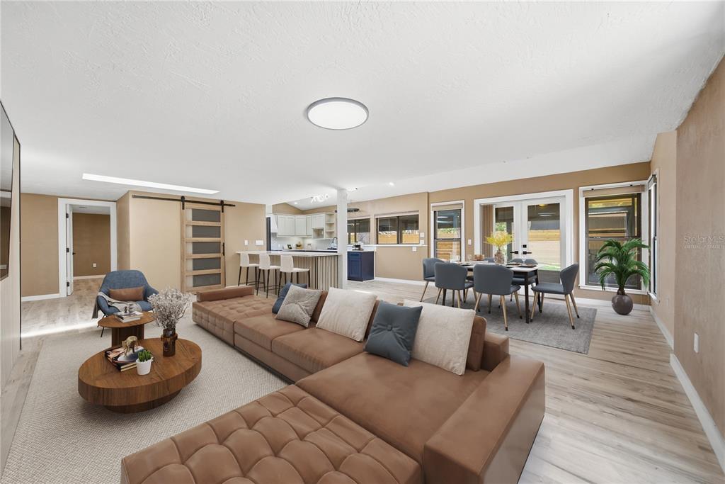 A living room with a large brown sectional sofa, dining area, and open kitchen — 7247 OELSNER STREET, NEW PORT RICHEY, FL