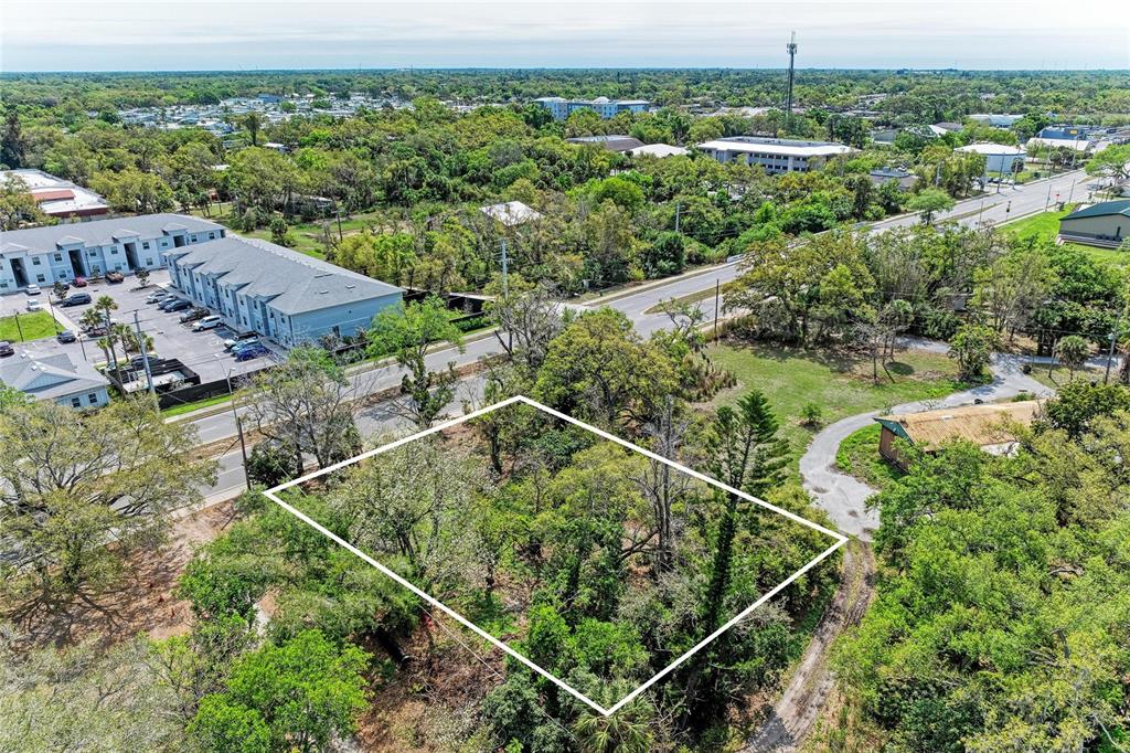 An aerial view shows a rectangular, tree-covered vacant lot outlined in white near a road — 820 S BENEVA ROAD, SARASOTA, FL