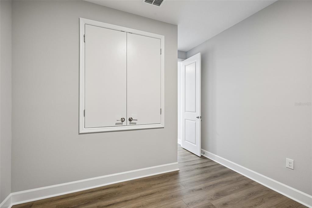 A room with light gray walls, wood-look flooring, and a white double-door wall cabinet — 3233 WOLF LAKE AVENUE, APOPKA, FL