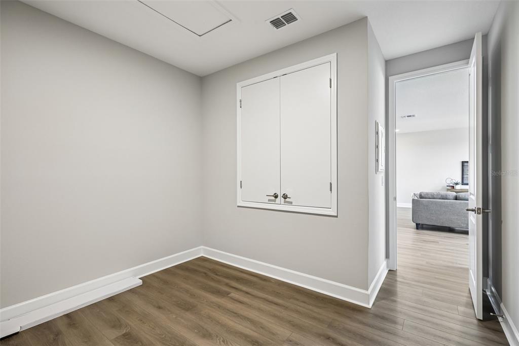A small room with light gray walls, wood-look flooring, and a white double-door wall cabinet — 3233 WOLF LAKE AVENUE, APOPKA, FL