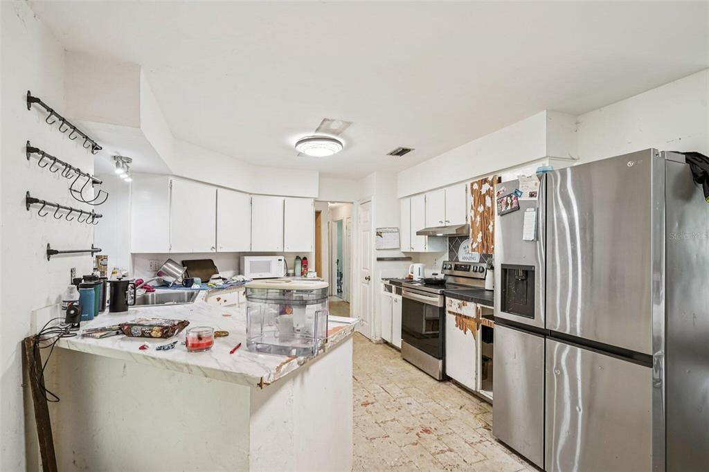 A kitchen with white cabinets, stainless steel appliances, a marble-look countertop, and tiled flooring — 15019 NW 134TH TERRACE, ALACHUA, FL