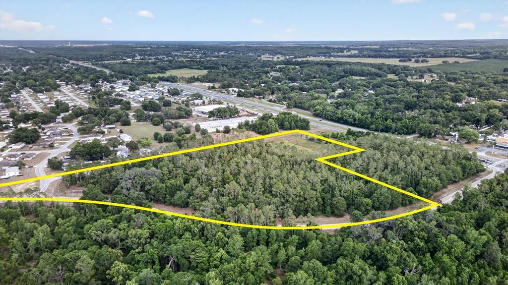 An aerial view shows a wooded plot of land outlined in yellow near a highway — 0 MONDON HILL ROAD, BROOKSVILLE, FL