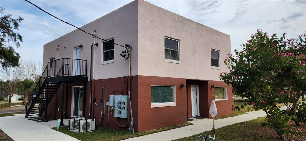 A two-story building with a two-tone stucco exterior and an external metal staircase — 1147 E MCDONALD AVENUE UNIT 202, EUSTIS, FL