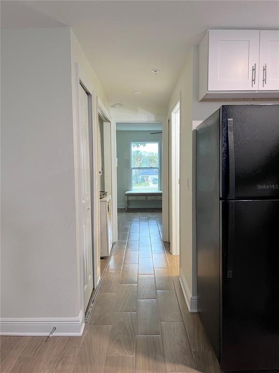 A hallway with wood-look tile flooring leads to a room with a window and bench — 1147 E MCDONALD AVENUE UNIT 202, EUSTIS, FL