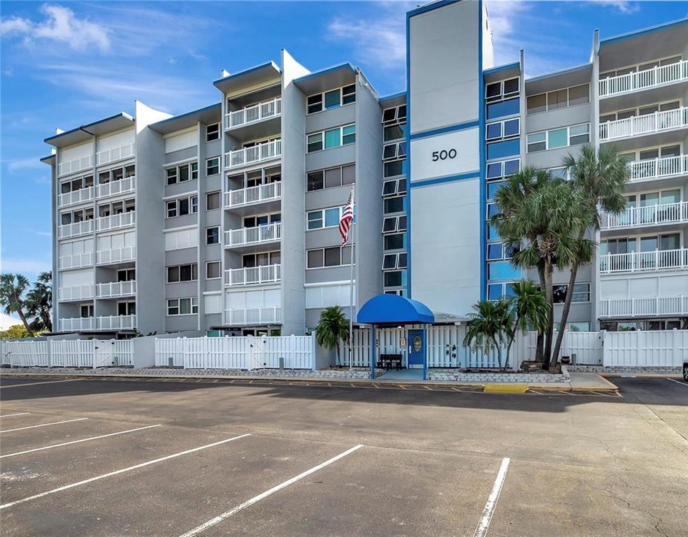 A multi-story apartment building with balconies, a blue entrance awning, and a parking lot — 500 TREASURE ISLAND CAUSEWAY UNIT 308, TREASURE ISLAND, FL