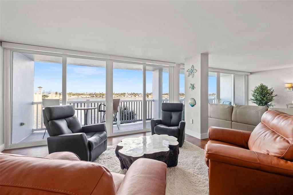 A living room with leather furniture, a unique coffee table, and a balcony overlooking water — 500 TREASURE ISLAND CAUSEWAY UNIT 308, TREASURE ISLAND, FL