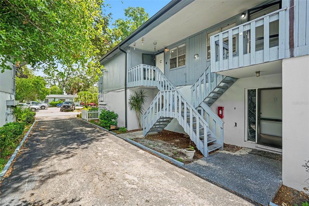Exterior view of a two-story apartment building with an outdoor staircase and paved driveway — 9208 N CONNECHUSETT ROAD UNIT C, TAMPA, FL