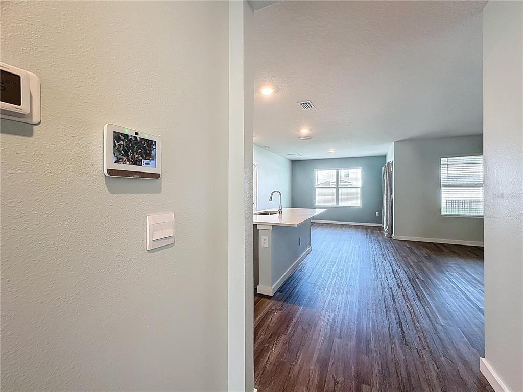 A view from a hallway into an open-concept kitchen and living area with wood flooring — 3707 HATCHERY WAY, BRADENTON, FL