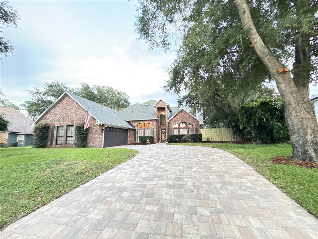 A brick house with a paved driveway and a large tree in the front yard — 9918 BAY VISTA ESTATES BOULEVARD, ORLANDO, FL