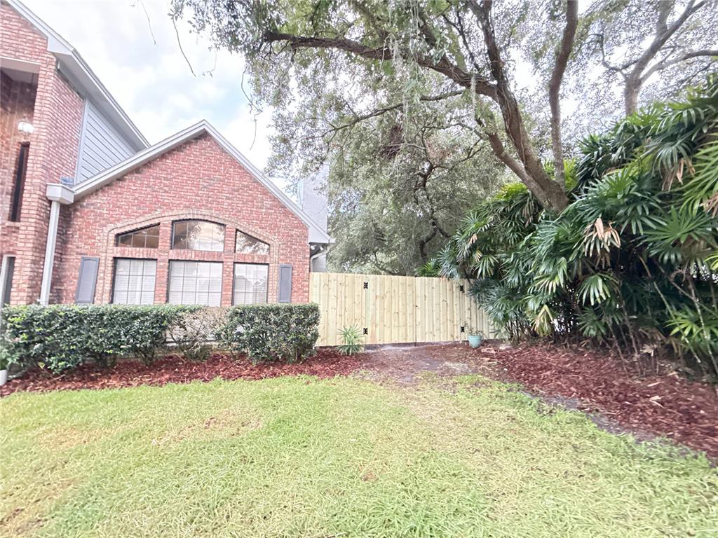 A brick house exterior features a large arched window, a wooden fence, and landscaping — 9918 BAY VISTA ESTATES BOULEVARD, ORLANDO, FL