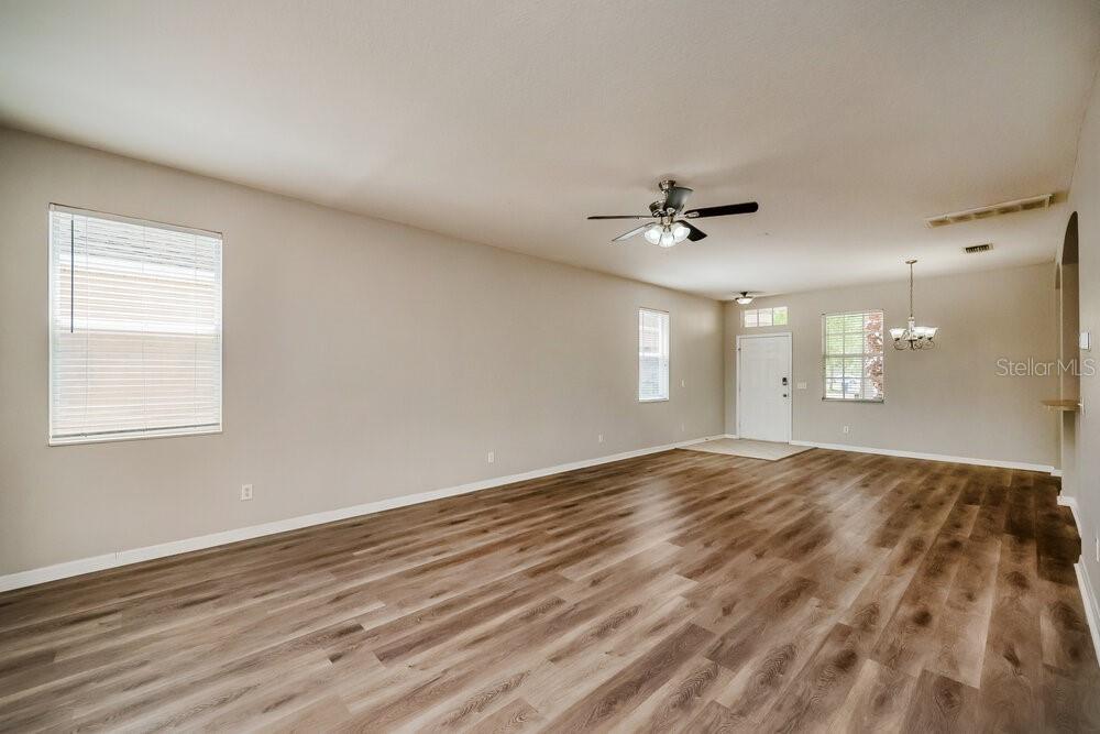 An empty living room features light-colored walls, wood-look flooring, and a ceiling fan — 908 LARWOOD PINE DRIVE, RUSKIN, FL