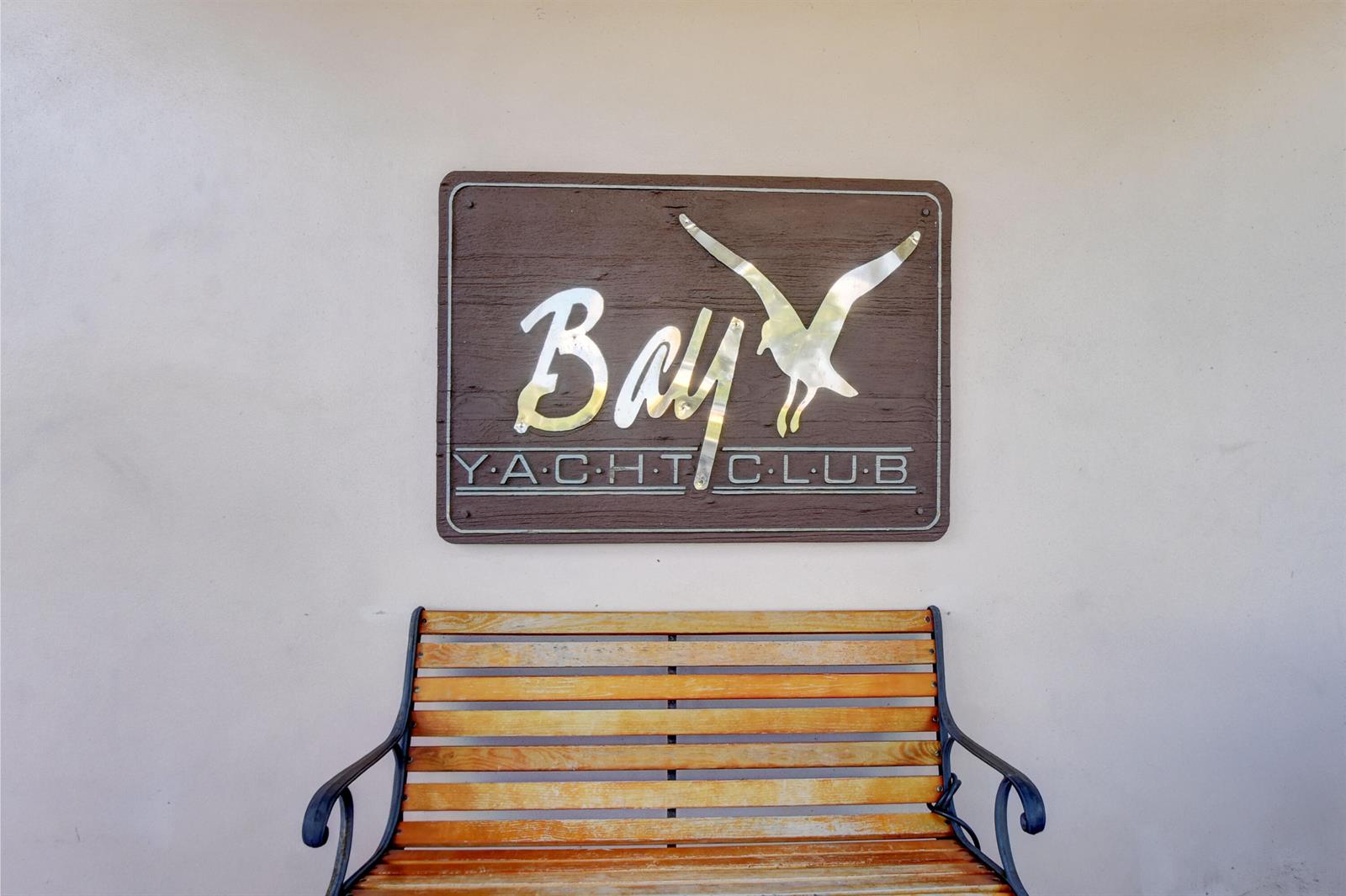 A wooden bench sits beneath a sign for the Bay Yacht Club on a wall — 740 S Federal Highway # 208, Pompano Beach FL 33062, POMPANO BEACH, FL