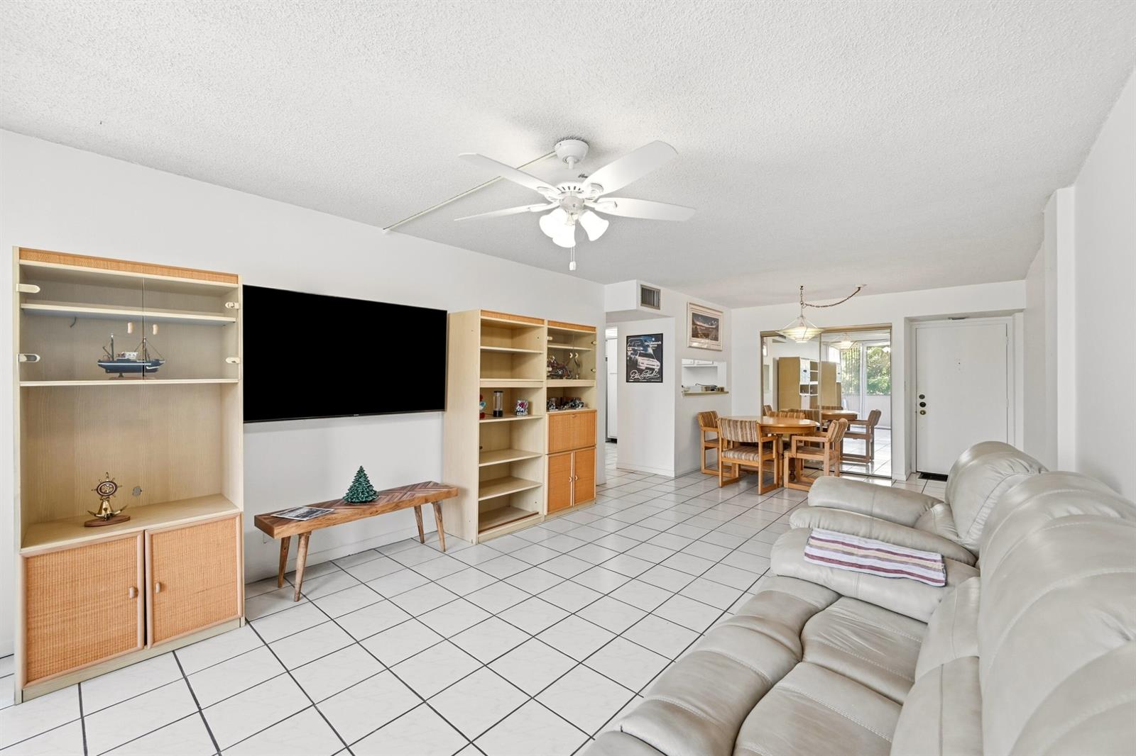 A living room with white tile floors, a ceiling fan, and built-in wooden shelving units — 740 S Federal Highway # 208, Pompano Beach FL 33062, POMPANO BEACH, FL