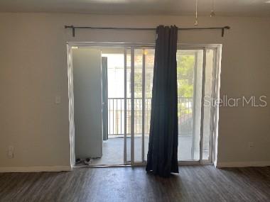 A room with wood-look flooring features a sliding glass door leading to a balcony — 7210 N MANHATTAN AVENUE UNIT 621, TAMPA, FL