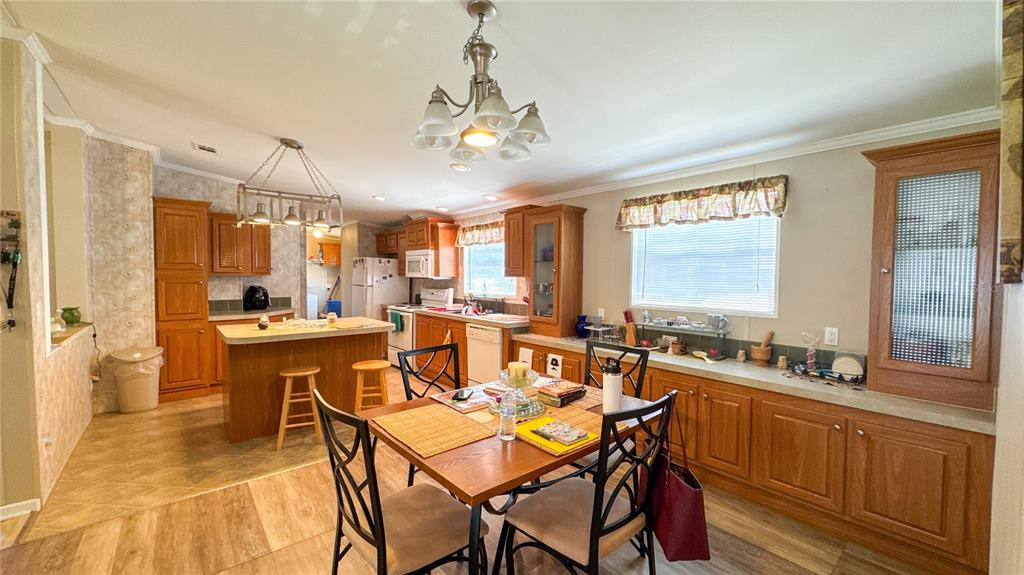 A kitchen and dining area featuring wood cabinets, a central island, and a dining table — 1503 ALBY DRIVE lot 70, APOPKA, FL