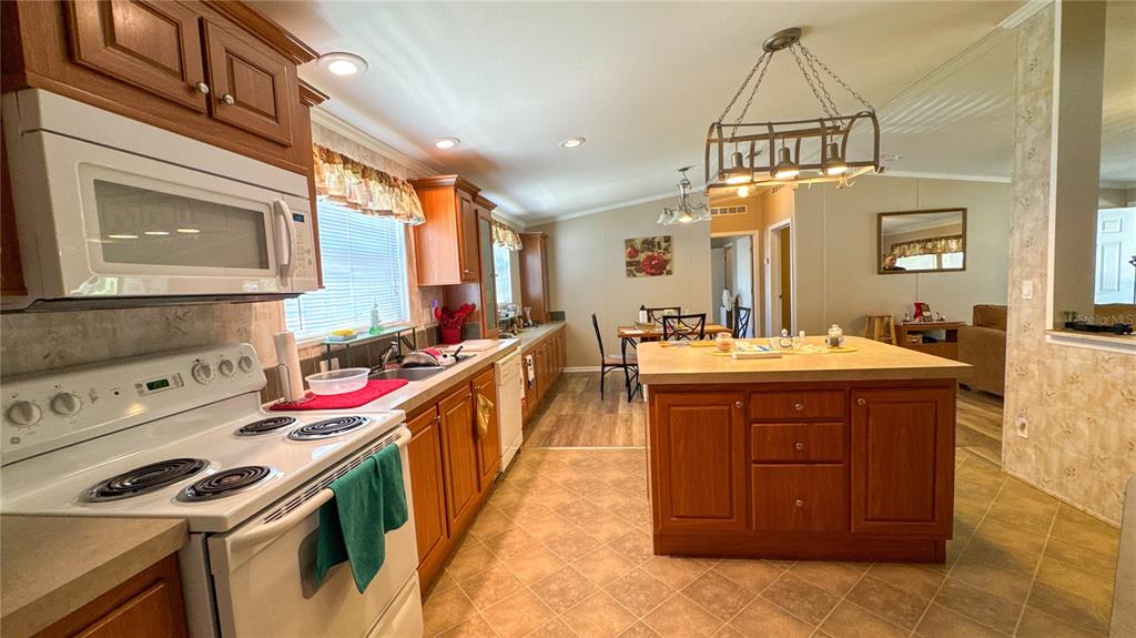 A kitchen features wood cabinets, a center island, and a white stove with a microwave — 1503 ALBY DRIVE lot 70, APOPKA, FL