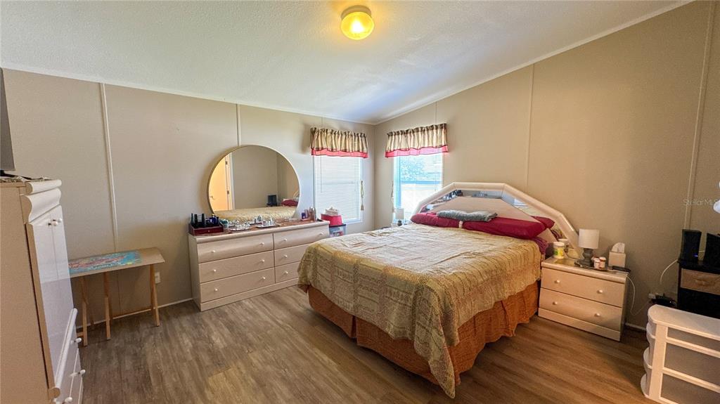 A bedroom features a bed, dresser with a round mirror, and light-colored wood-look flooring — 1503 ALBY DRIVE lot 70, APOPKA, FL