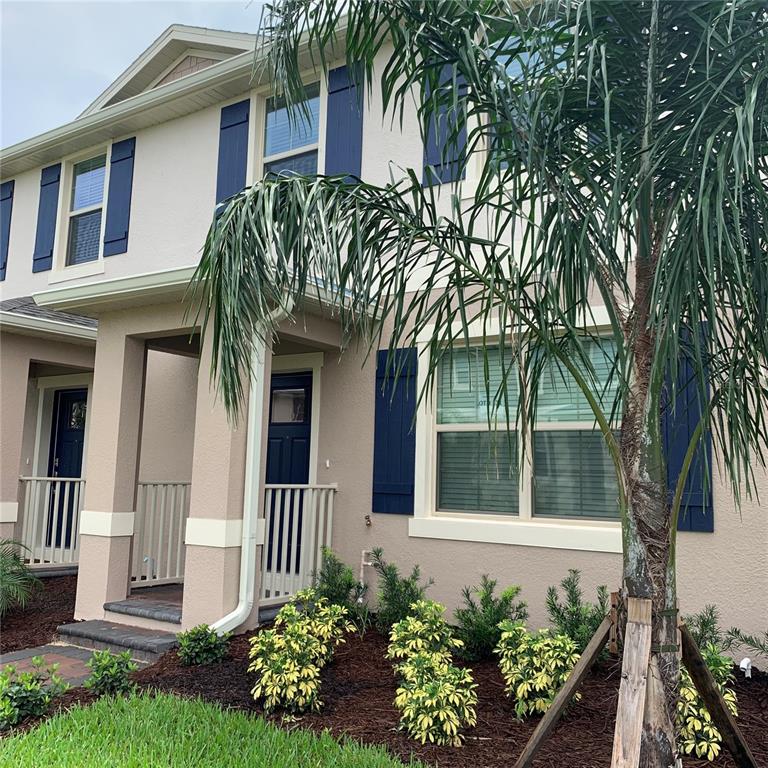 A two-story tan house features blue shutters, a covered porch, and a palm tree — 10094 TAWNY MEADOW ALLEY, WINTER GARDEN, FL