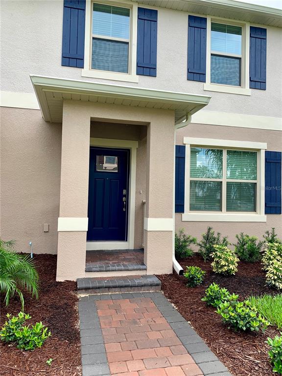 The exterior of a two-story house features a blue front door and blue shutters — 10094 TAWNY MEADOW ALLEY, WINTER GARDEN, FL