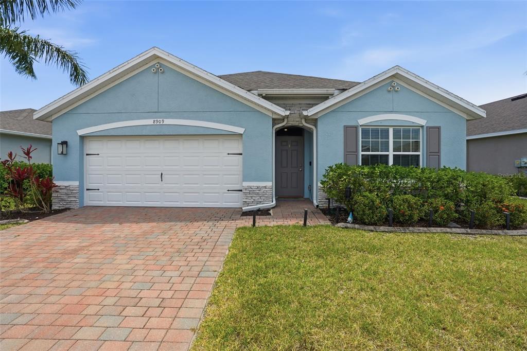 A light blue single-story house with a brick driveway and a two-car garage — 8909 CASCADE PRICE CIRCLE, NORTH FORT MYERS, FL