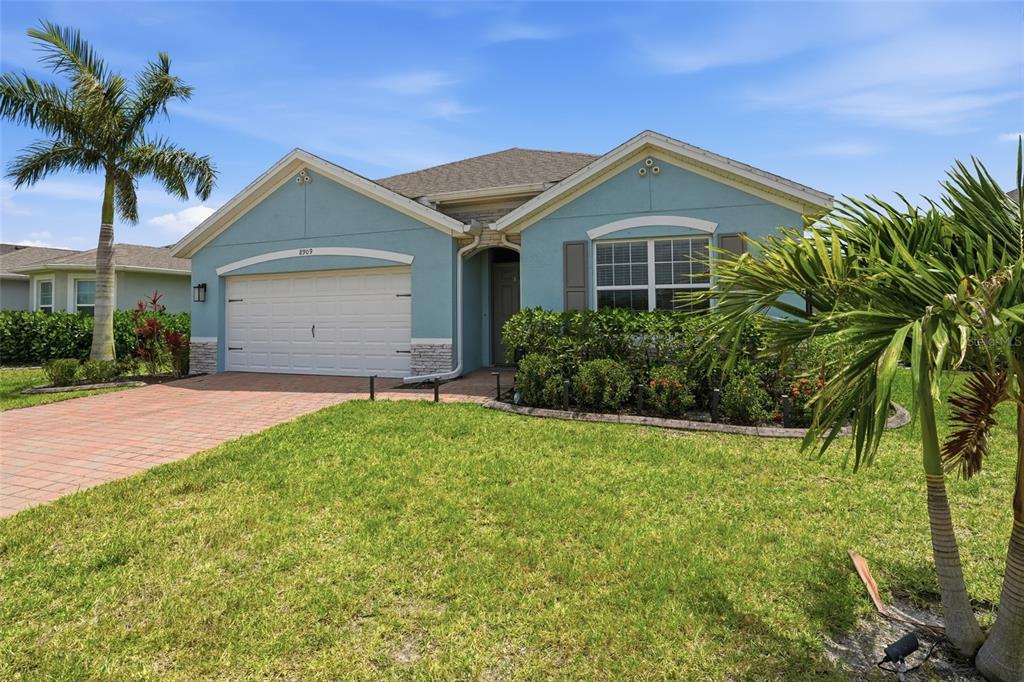 A light blue single-story house with a two-car garage and a paved driveway — 8909 CASCADE PRICE CIRCLE, NORTH FORT MYERS, FL