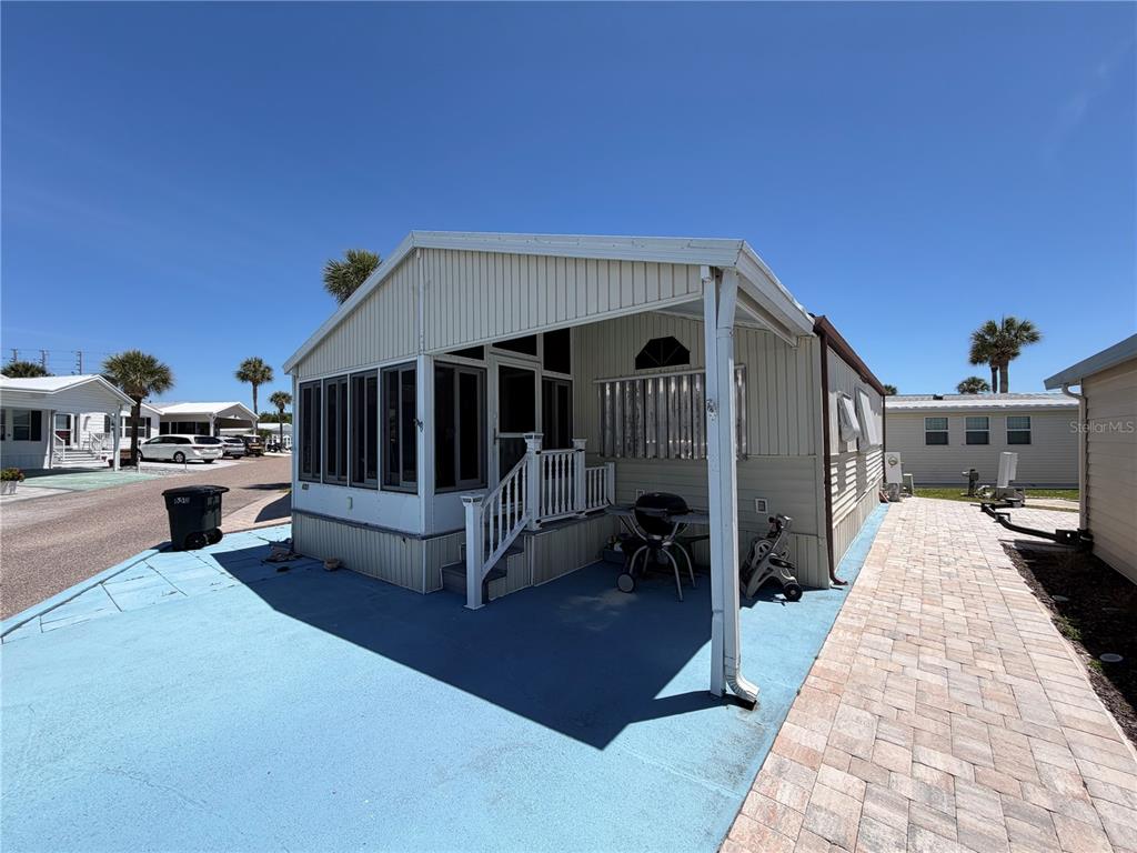 A manufactured home with a screened-in porch, blue concrete patio, and paver walkway — 9000 US HIGHWAY 192 UNIT 650, CLERMONT, FL