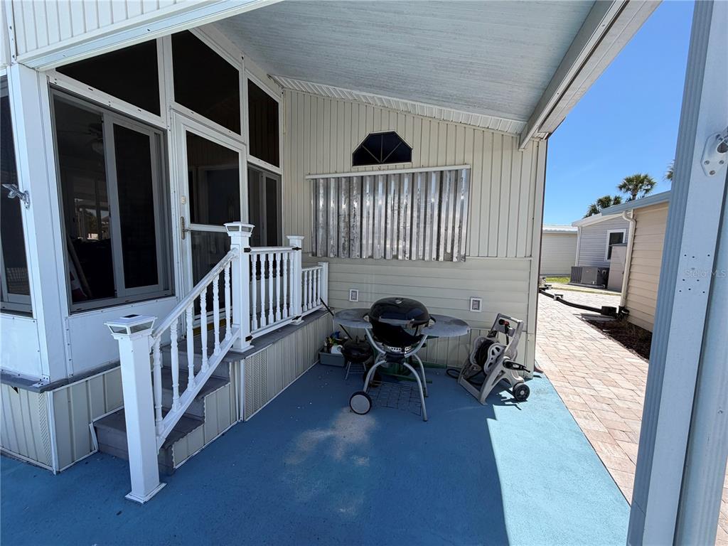 A covered patio features a blue floor, white railing, stairs, and a charcoal grill — 9000 US HIGHWAY 192 UNIT 650, CLERMONT, FL
