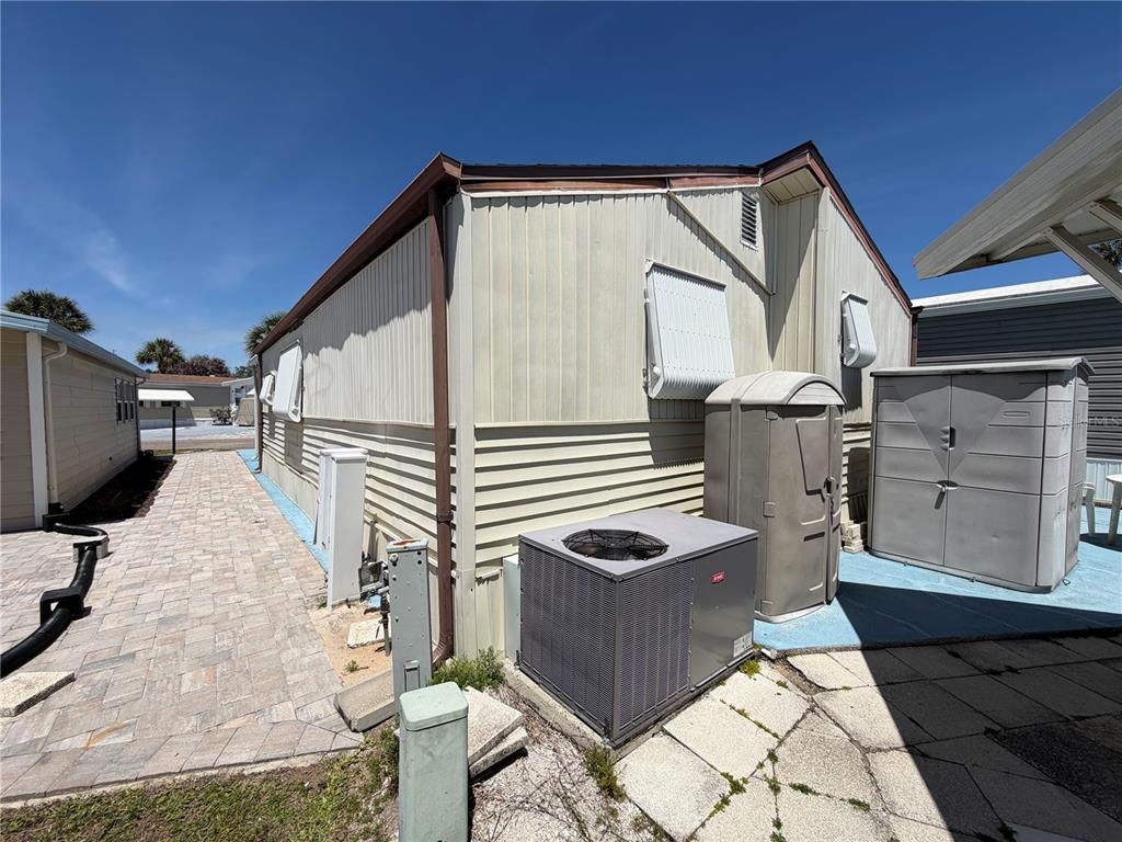 The exterior of a mobile home features light-colored siding, an air conditioning unit, and storage sheds — 9000 US HIGHWAY 192 UNIT 650, CLERMONT, FL